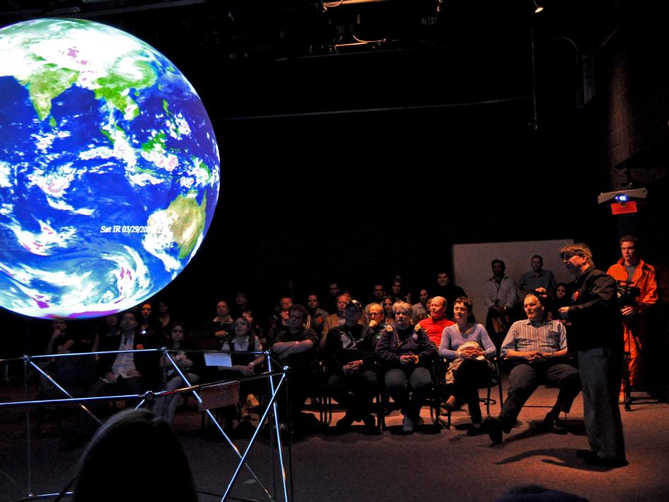 Image showing Dr. James Garvin (on right), giving a presentation on "Science On a Sphere" to Yuri's Night guests. 